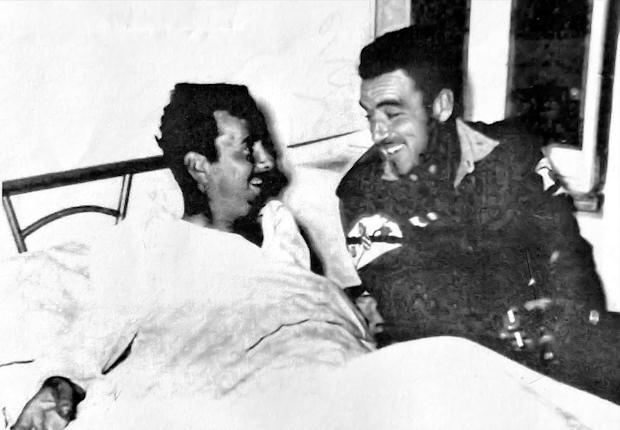 El capitán Emilio Rosaleny Giménez postrado en la cama recibe la visita de su amigo y compañero el capitán paracaidista Juan Sánchez Duque.