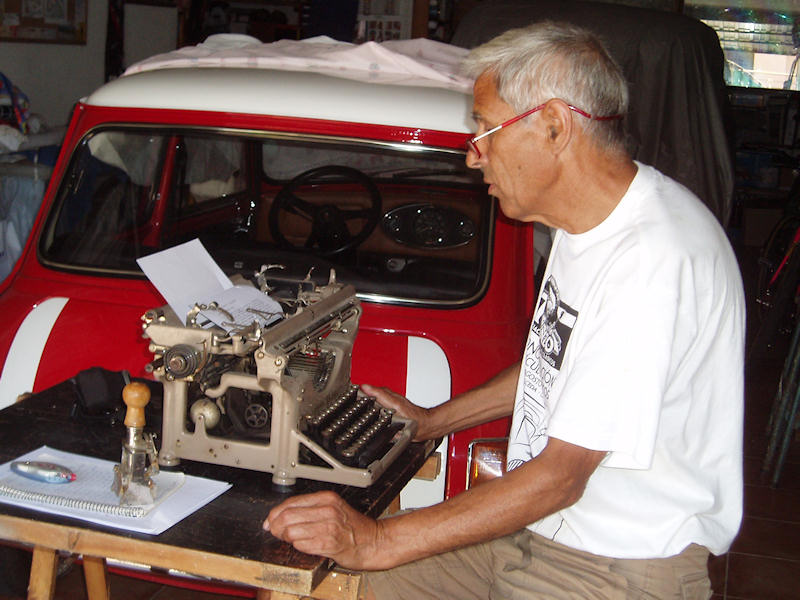 Efrén Gómez, en el garaje de su casa escribiendo una reseña de un encuentro de veteranos con una de sus aficiones, las máquinas de escribir antiguas, junto a otra, los coches antiguos.