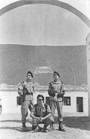 Paracaidistas y Legionarios bajo el arco del acuartelamiento. Al fondo sus escudos (Foto Web)